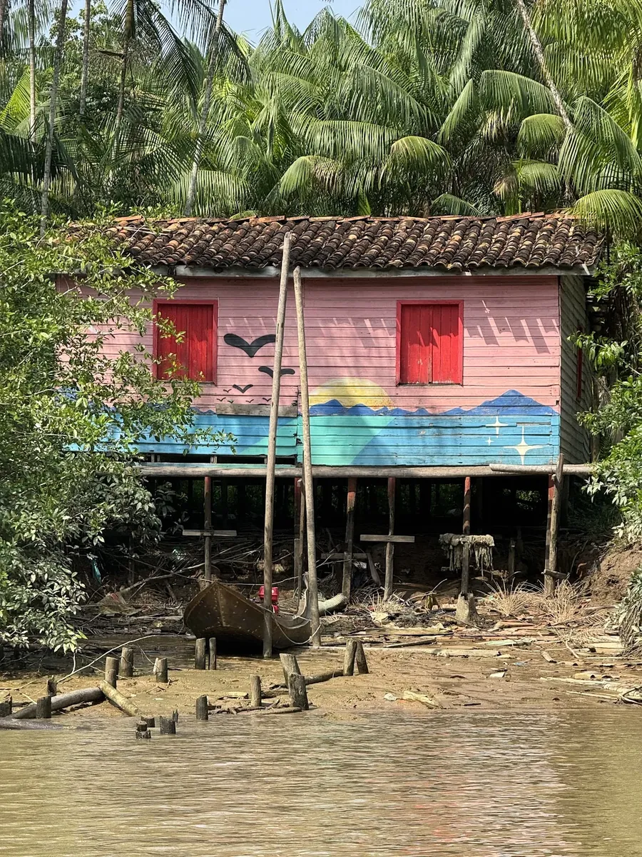 Casa ribeirinha colorida sobre palafitas à beira do rio no Combu
