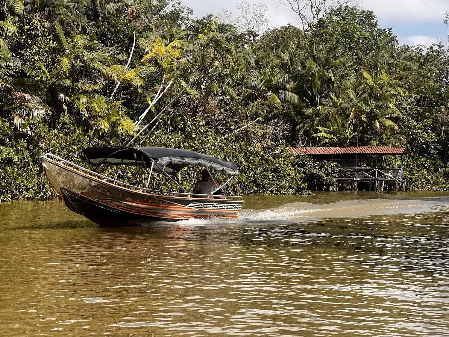 Barco da Monotour navegando por um igarapé cercado de floresta na Ilha do Combu